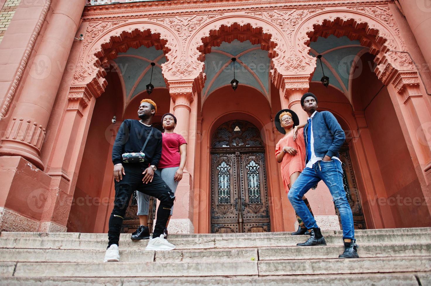 quattro amici africani hanno posato all'aperto contro la vecchia architettura. due ragazze nere con ragazzi. foto