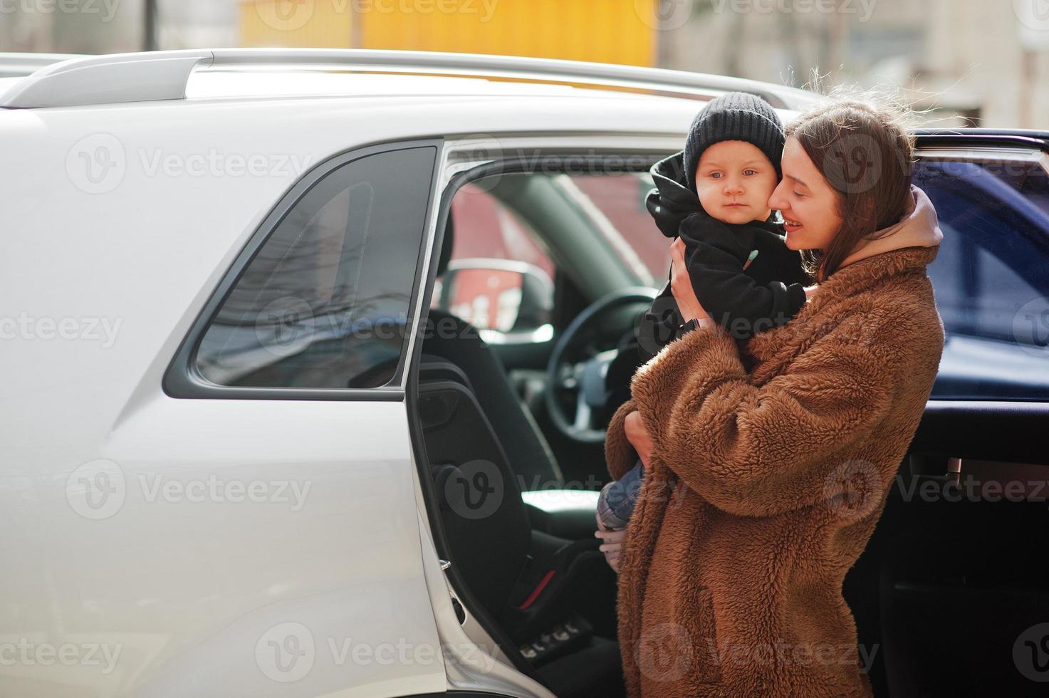 la giovane madre e il bambino stanno vicino alla loro auto suv. concetto di guida di sicurezza. foto