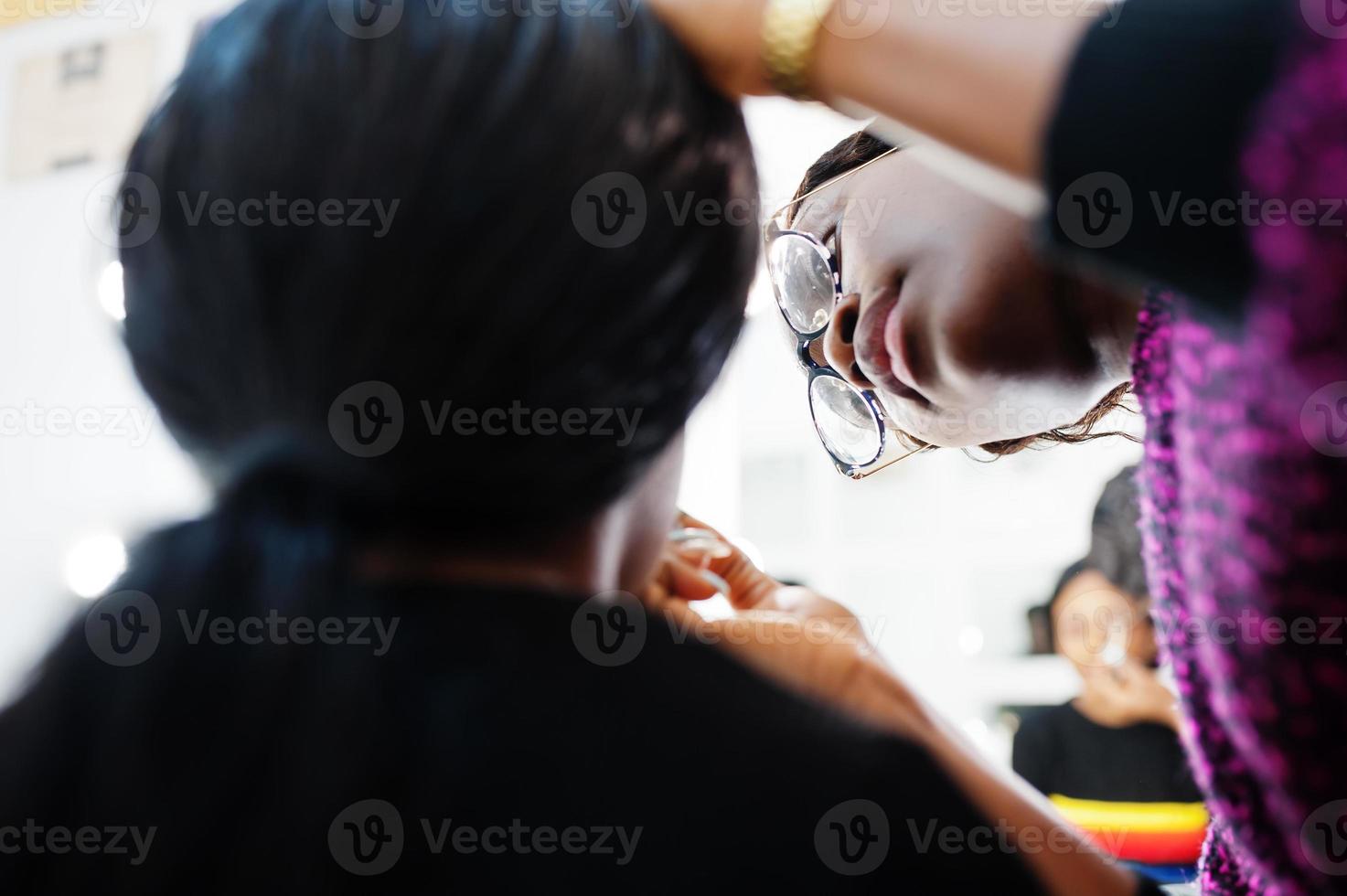 donna afroamericana che applica il trucco dal truccatore al salone di bellezza. foto