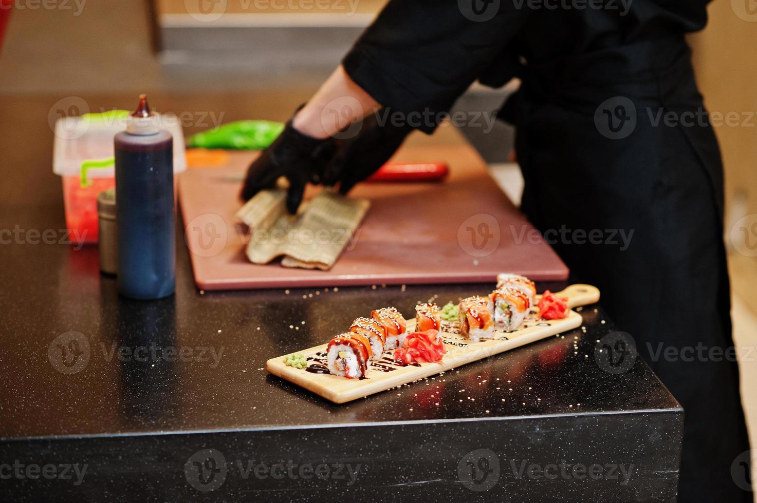 mani ravvicinate di chef professionisti indossano guanti neri che preparano sushi e panini in un ristorante cucina di cibo tradizionale giapponese. foto