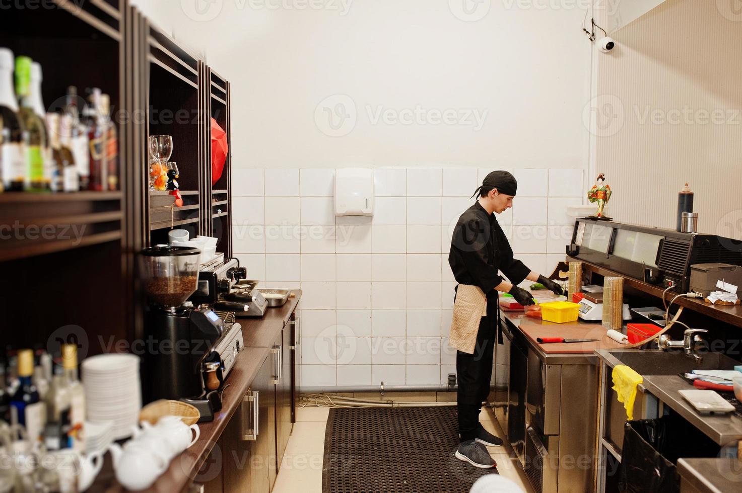 lo chef professionista indossa in nero facendo sushi e panini in una cucina del ristorante di cibo tradizionale giapponese. foto