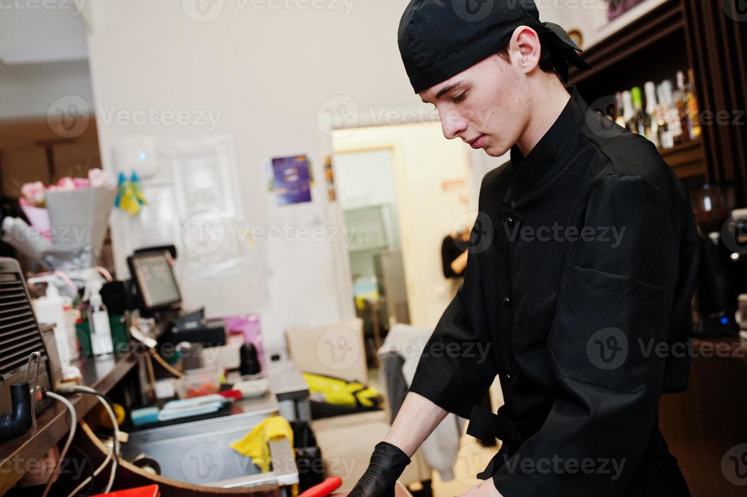 lo chef professionista indossa in nero facendo sushi e panini in una cucina del ristorante di cibo tradizionale giapponese. foto