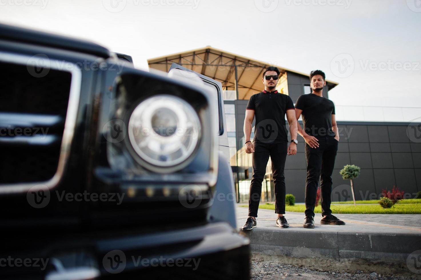 due fratelli asiatici indossano un uomo tutto nero in posa vicino a un'auto suv. foto