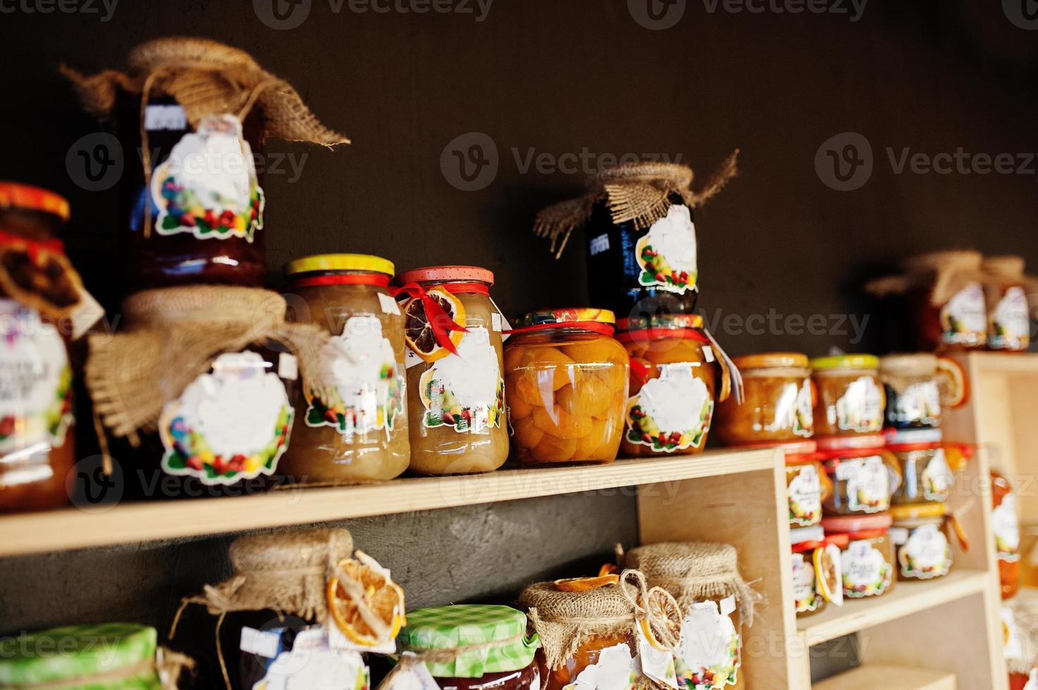 barattoli di vetro con diversi tipi di marmellata e frutti di bosco sugli scaffali di un supermercato o di un negozio di alimentari. prodotti conserviera fatti in casa. fatto con amore. foto