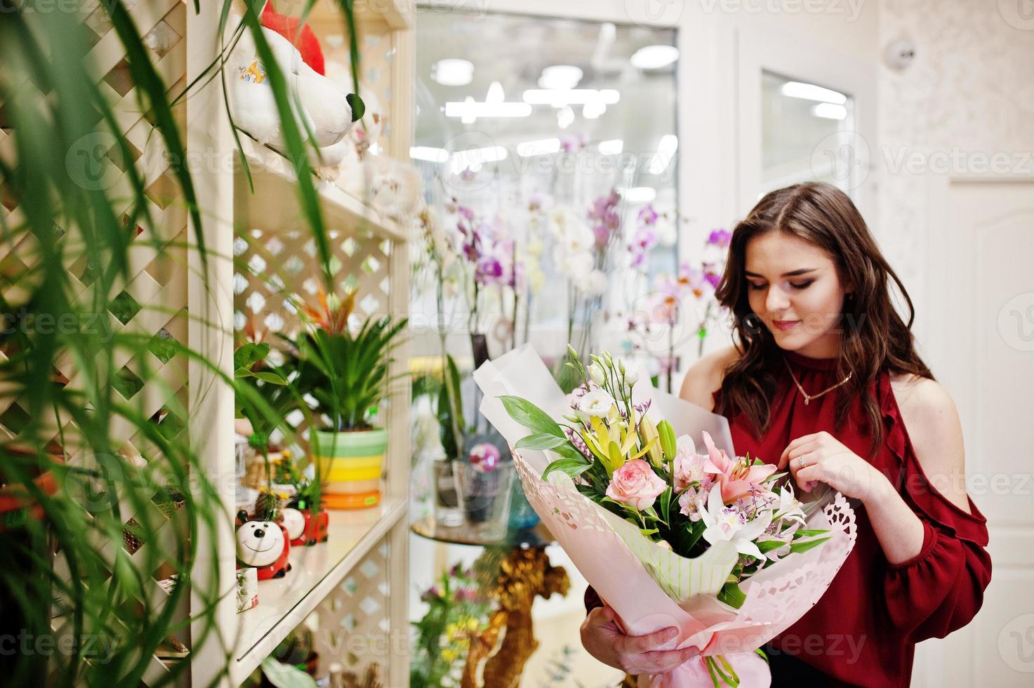 ragazza bruna in rosso comprare fiori al negozio di fiori. foto