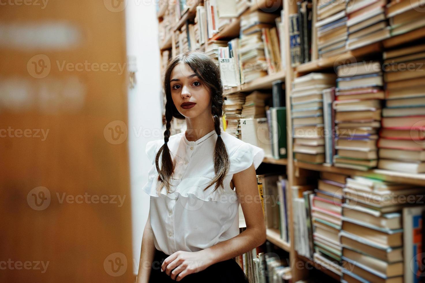 ragazza con le trecce in camicetta bianca alla vecchia biblioteca. foto