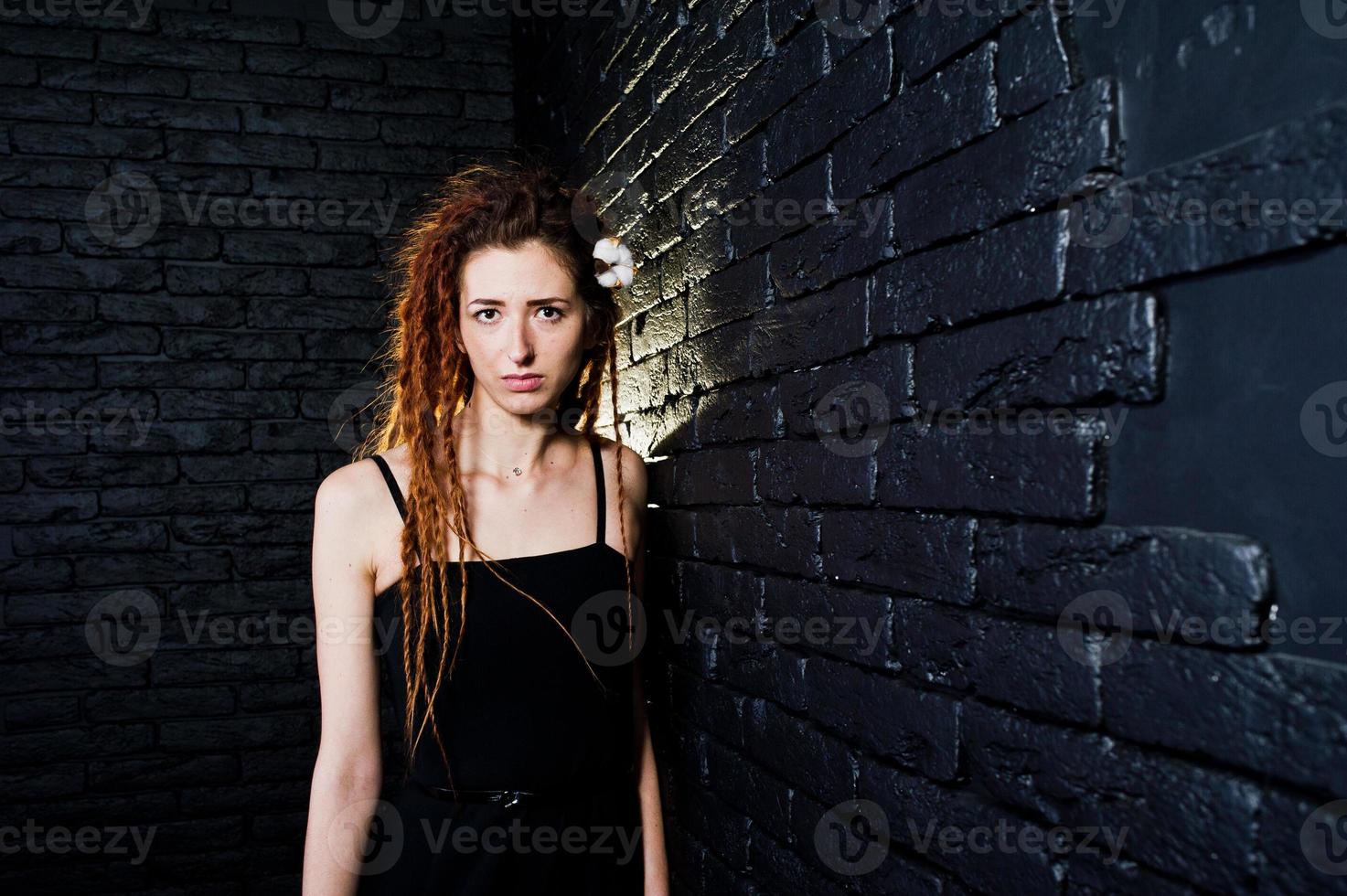 tiro in studio di una ragazza in nero con dreadlocks su sfondo di mattoni. foto