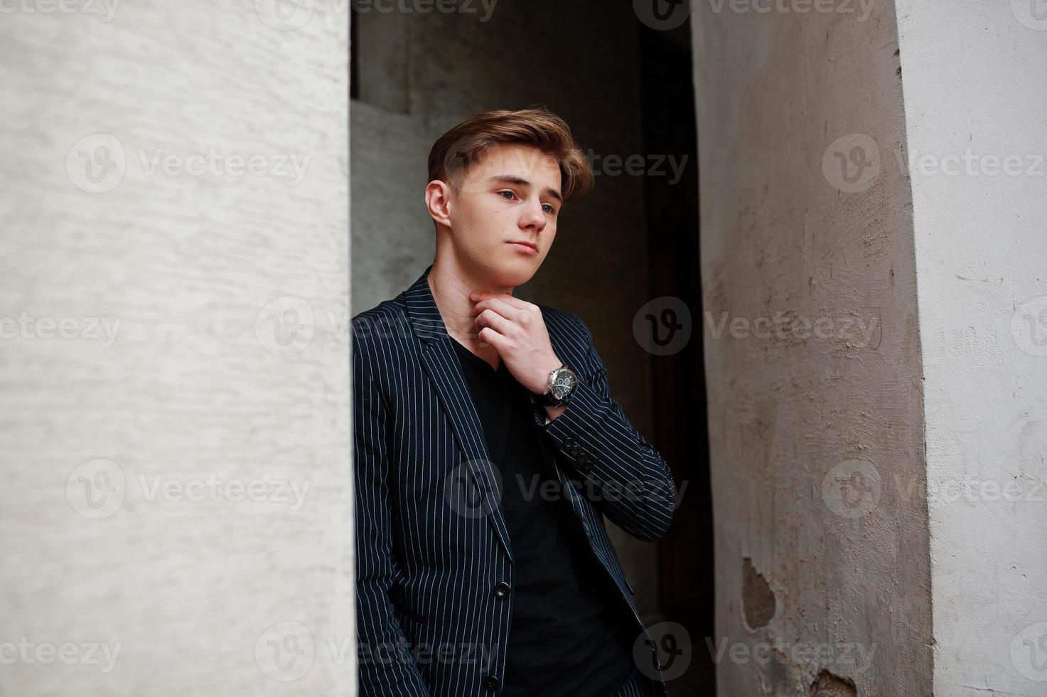 giovane ragazzo macho alla moda in giacca nera posato all'aperto di strada. fantastico uomo modello. foto