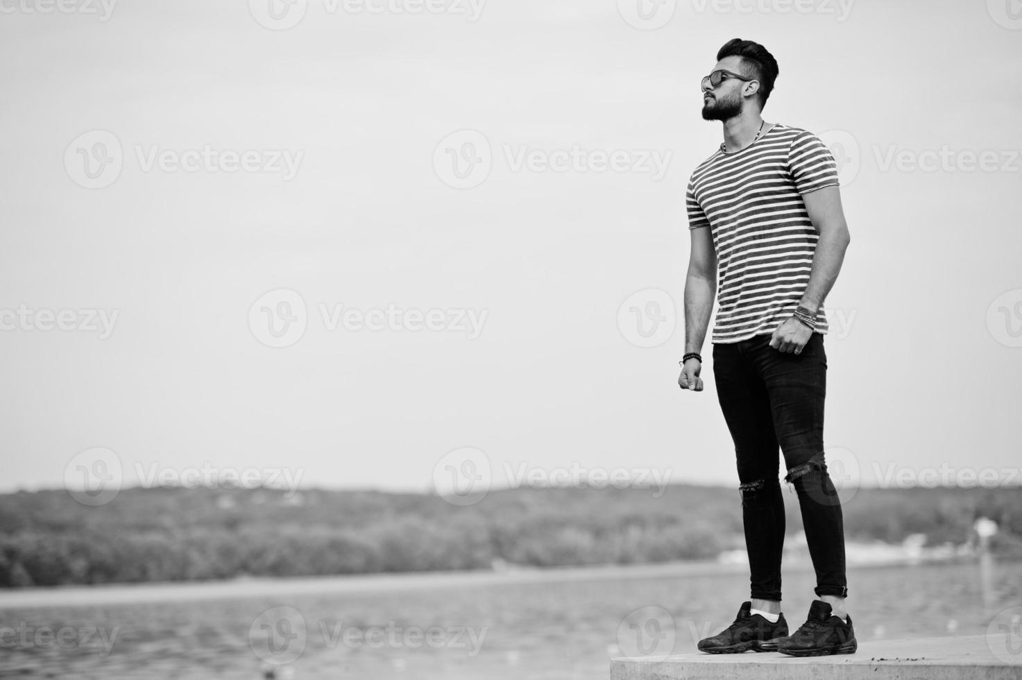 bel modello uomo alto con barba araba in camicia spogliata in posa all'aperto. ragazzo arabo alla moda con occhiali da sole. foto