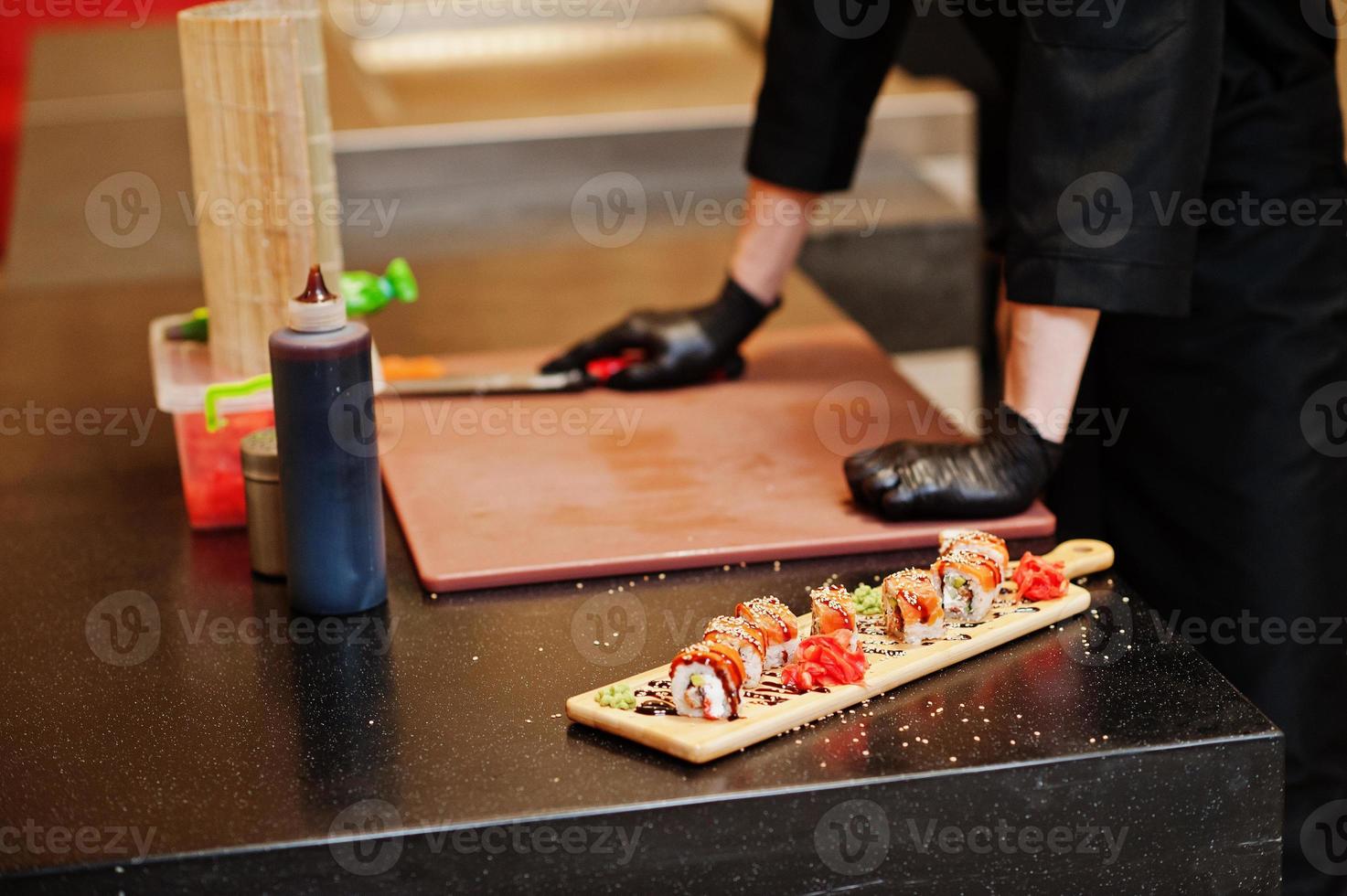 mani ravvicinate di chef professionisti indossano guanti neri che preparano sushi e panini in un ristorante cucina di cibo tradizionale giapponese. foto