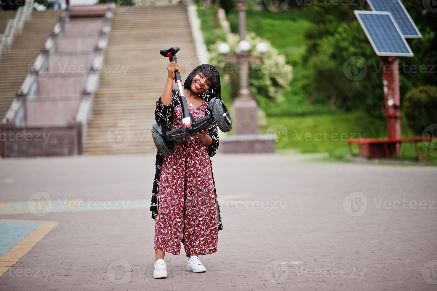 bella donna afroamericana tenersi per mano segway o hoverboard. ragazza nera con scooter elettrico autobilanciante a doppia ruota. foto