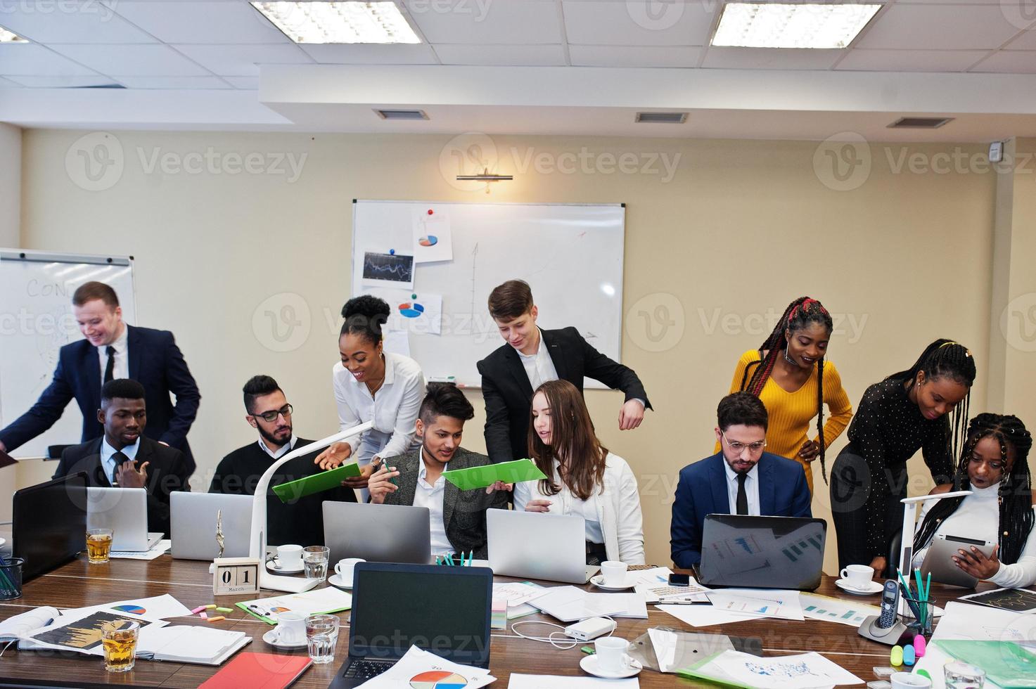 giovani creativi multirazziali in un ufficio moderno. gruppo di giovani uomini d'affari stanno lavorando insieme con laptop, tablet. team di freelance di successo nel coworking. foto