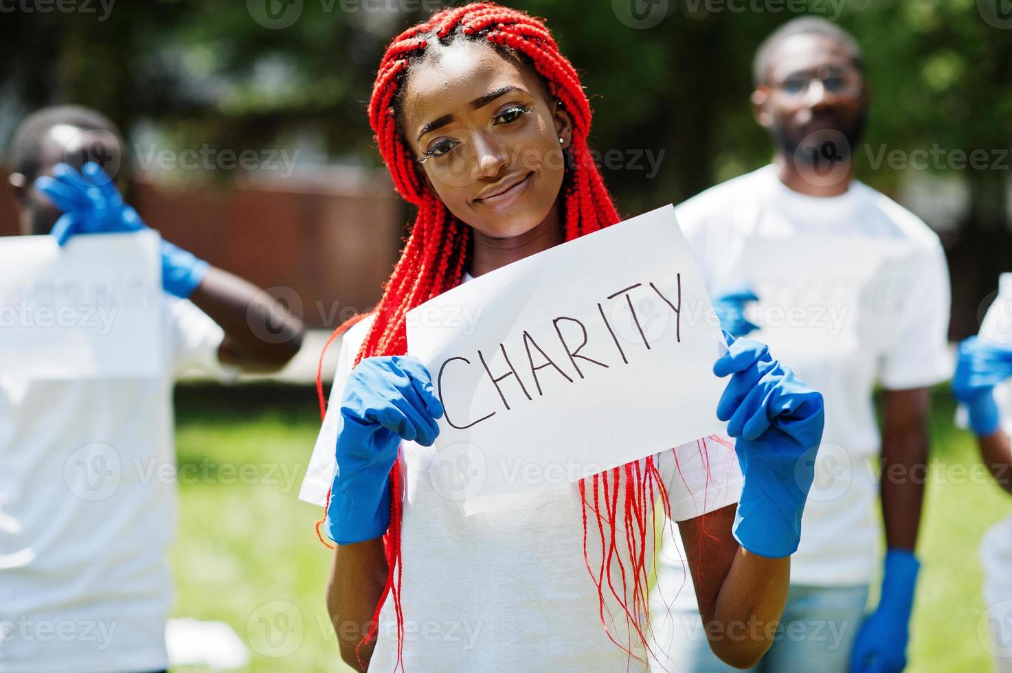 un gruppo di volontari africani felici tiene una lavagna vuota con un cartello di beneficenza nel parco. concetto di volontariato, carità, persone ed ecologia in africa. foto