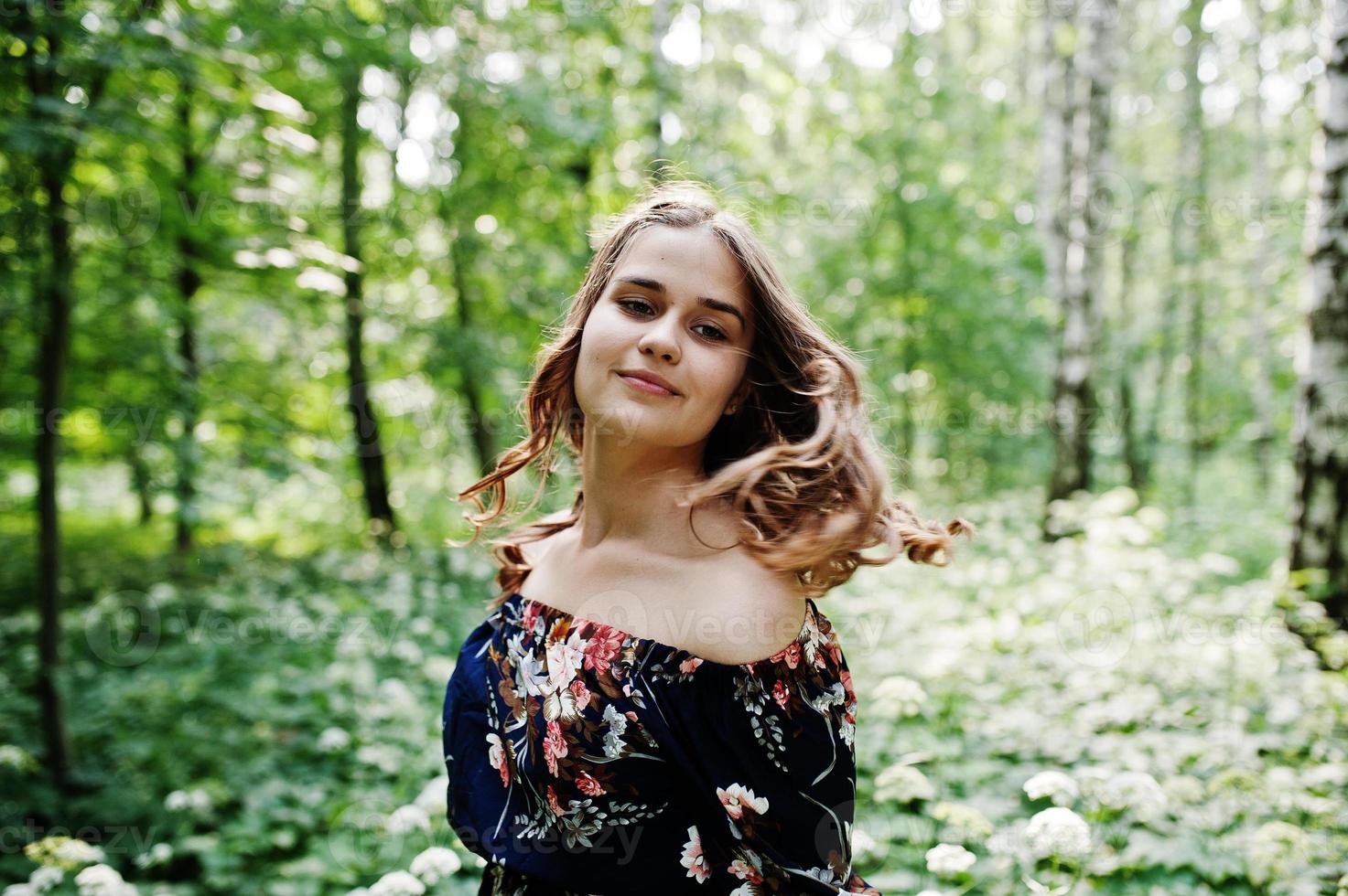 ritratto di una favolosa ragazza in un bel vestito con un'elegante acconciatura riccia in posa nella foresta o nel parco. foto