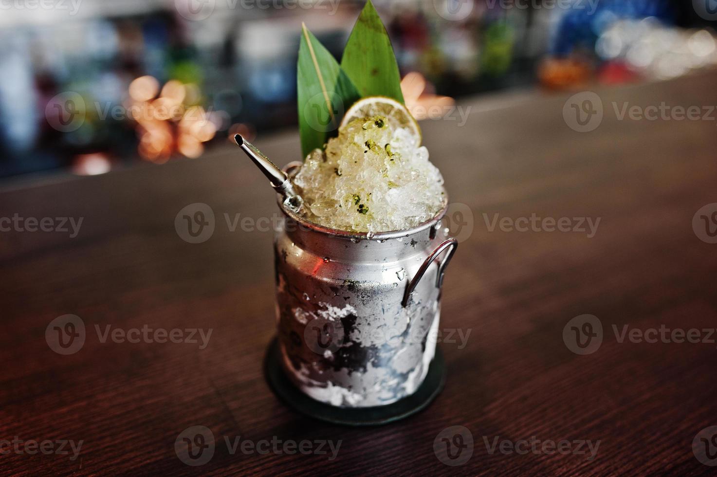 cocktail alcolico con ghiaccio in lattina di vetro sul tavolo da bar. foto