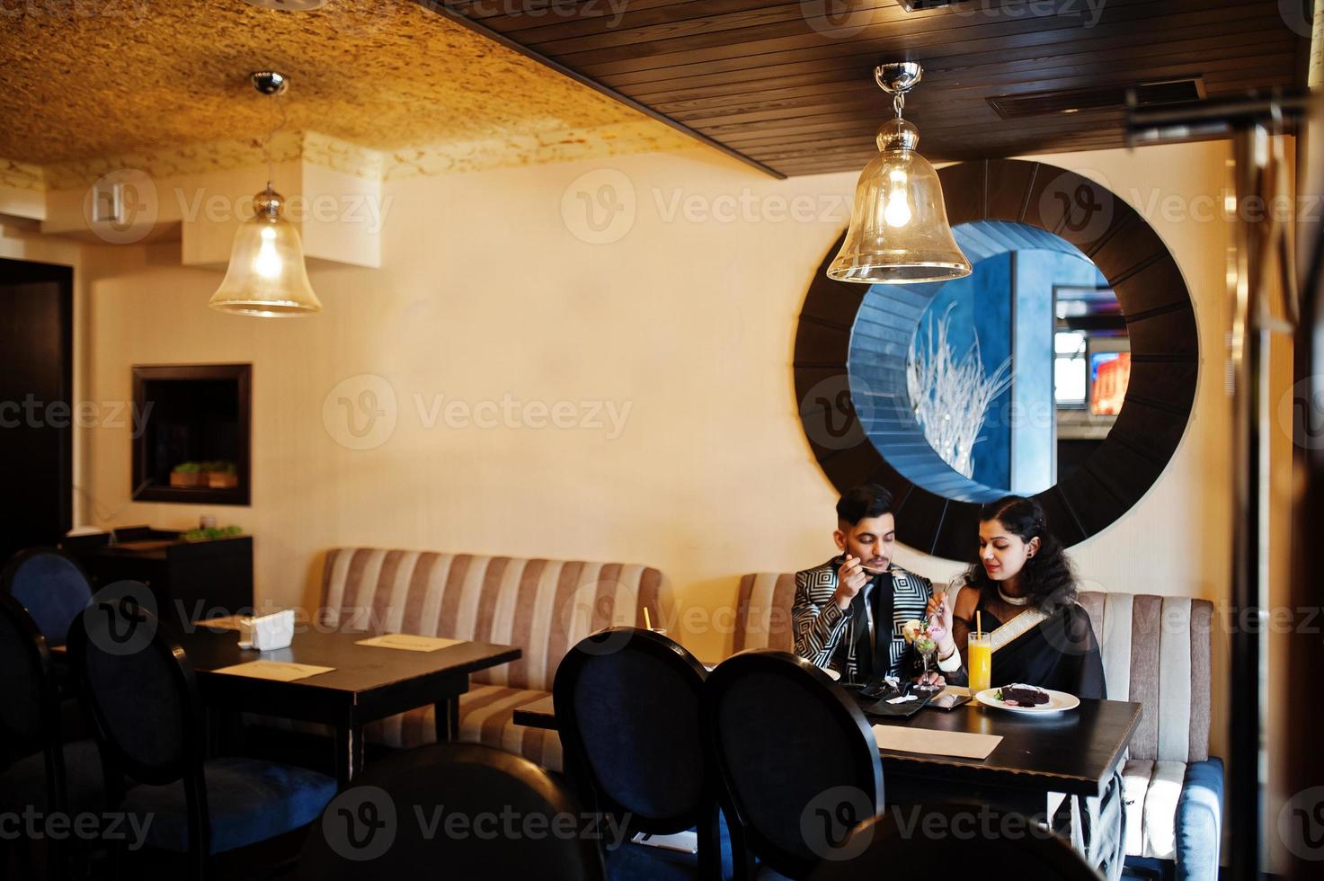 adorabile coppia indiana innamorata, indossata a saree e abito elegante, posata sul ristorante. foto