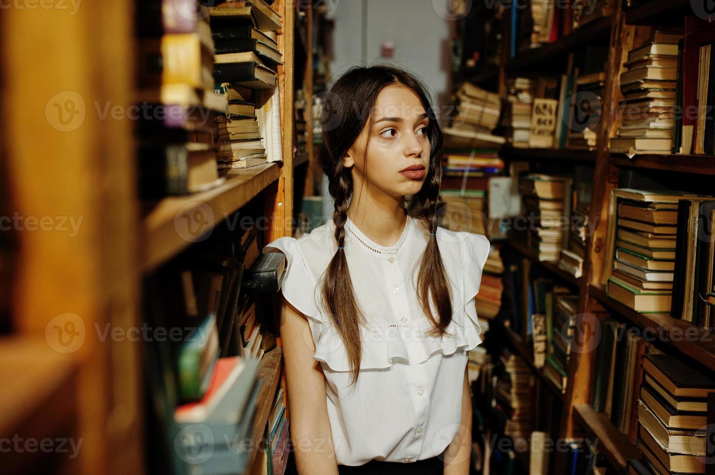 ragazza con le trecce in camicetta bianca alla vecchia biblioteca. foto