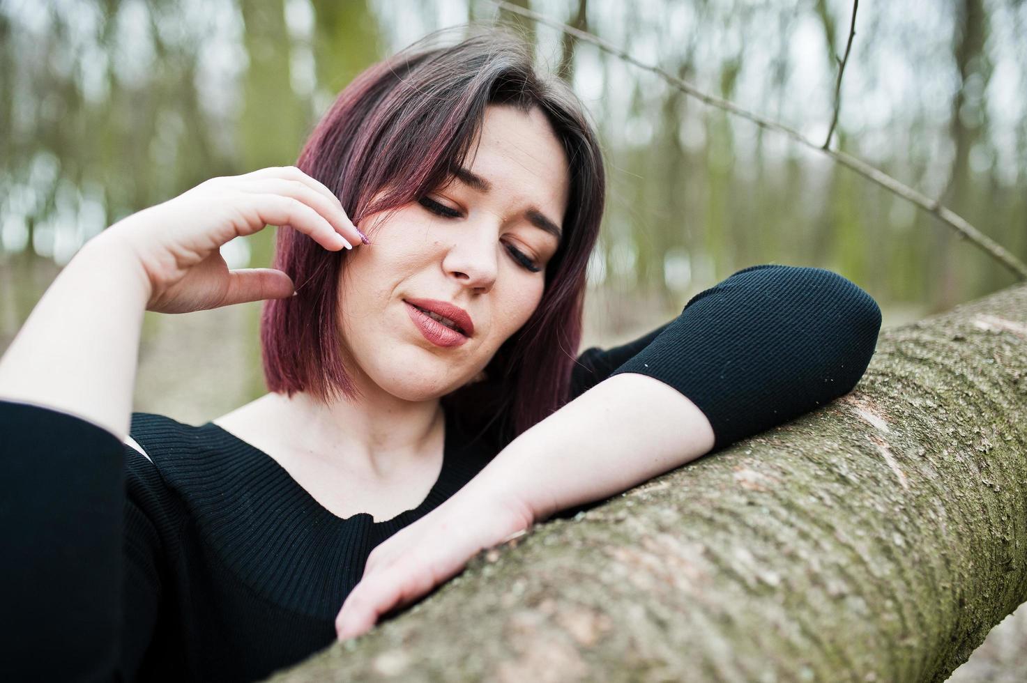 ritratto di ragazza bruna in abito nero in legno primaverile. foto