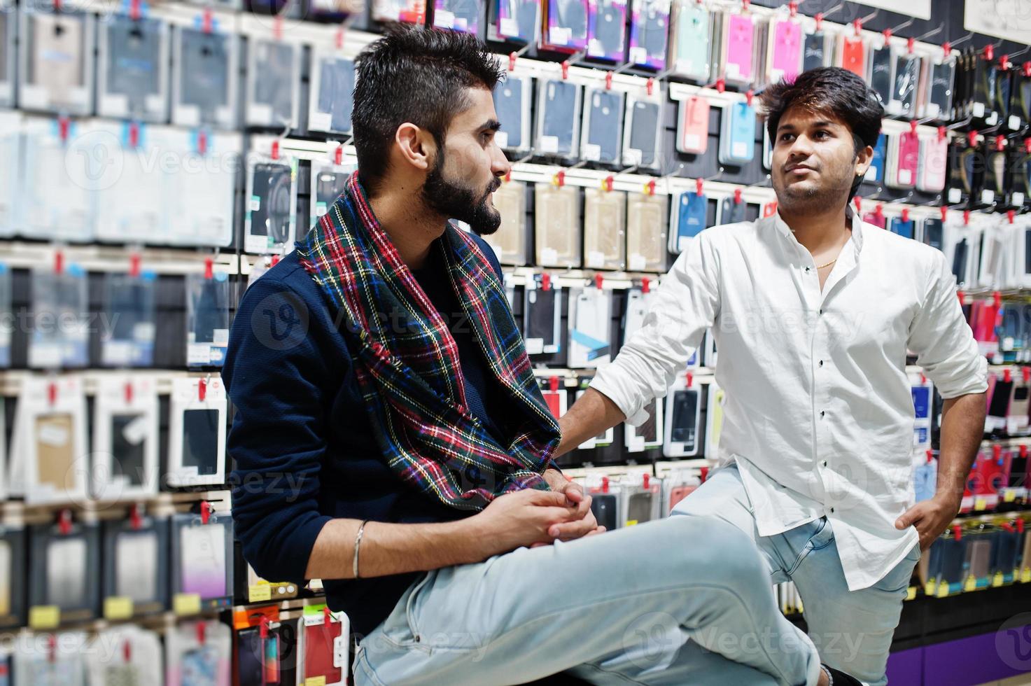 due acquirenti indiani di clienti presso un negozio di telefoni cellulari scelgono una custodia per il suo smartphone. concetto di popoli e tecnologie dell'Asia meridionale. negozio di cellulari. foto