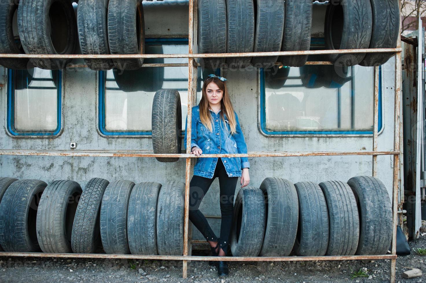 giovane ragazza hipster in giacca di jeans e sciarpa per la testa nella zona di montaggio dei pneumatici. foto