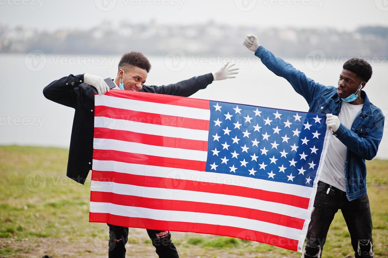 due adolescenti africani amici con bandiera americana al parco che indossano maschere mediche proteggono da infezioni e malattie quarantena del virus del coronavirus. foto