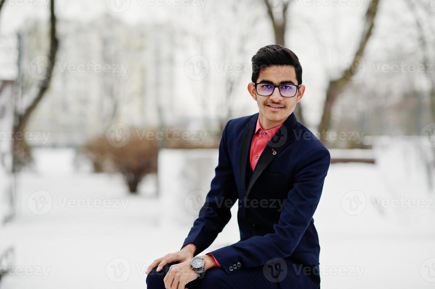 elegante studente indiano uomo in tuta e occhiali poste al giorno d'inverno all'aperto. foto