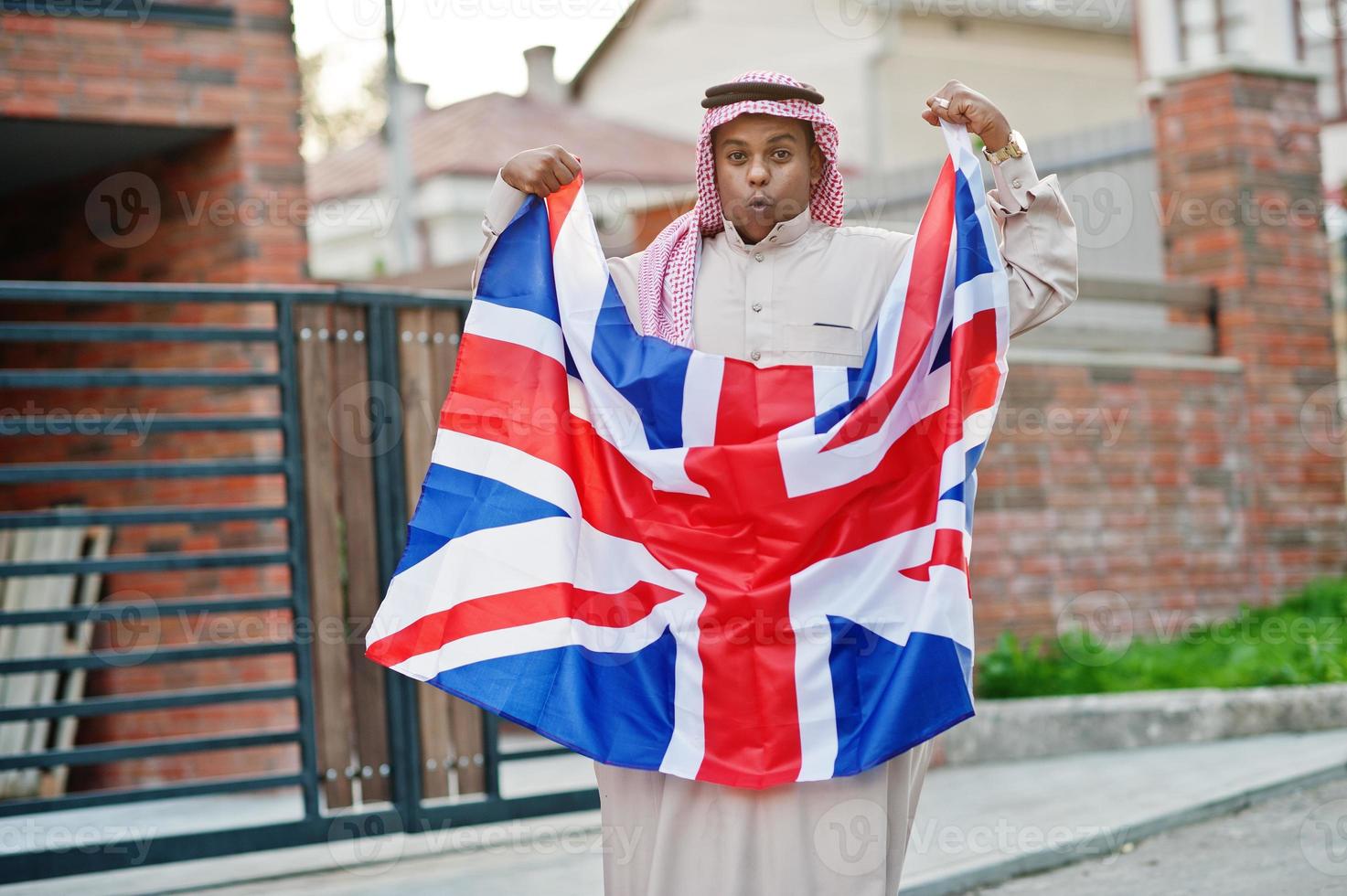 uomo arabo mediorientale posato su strada con bandiera della Gran Bretagna. concetto di inghilterra e paesi arabi. foto