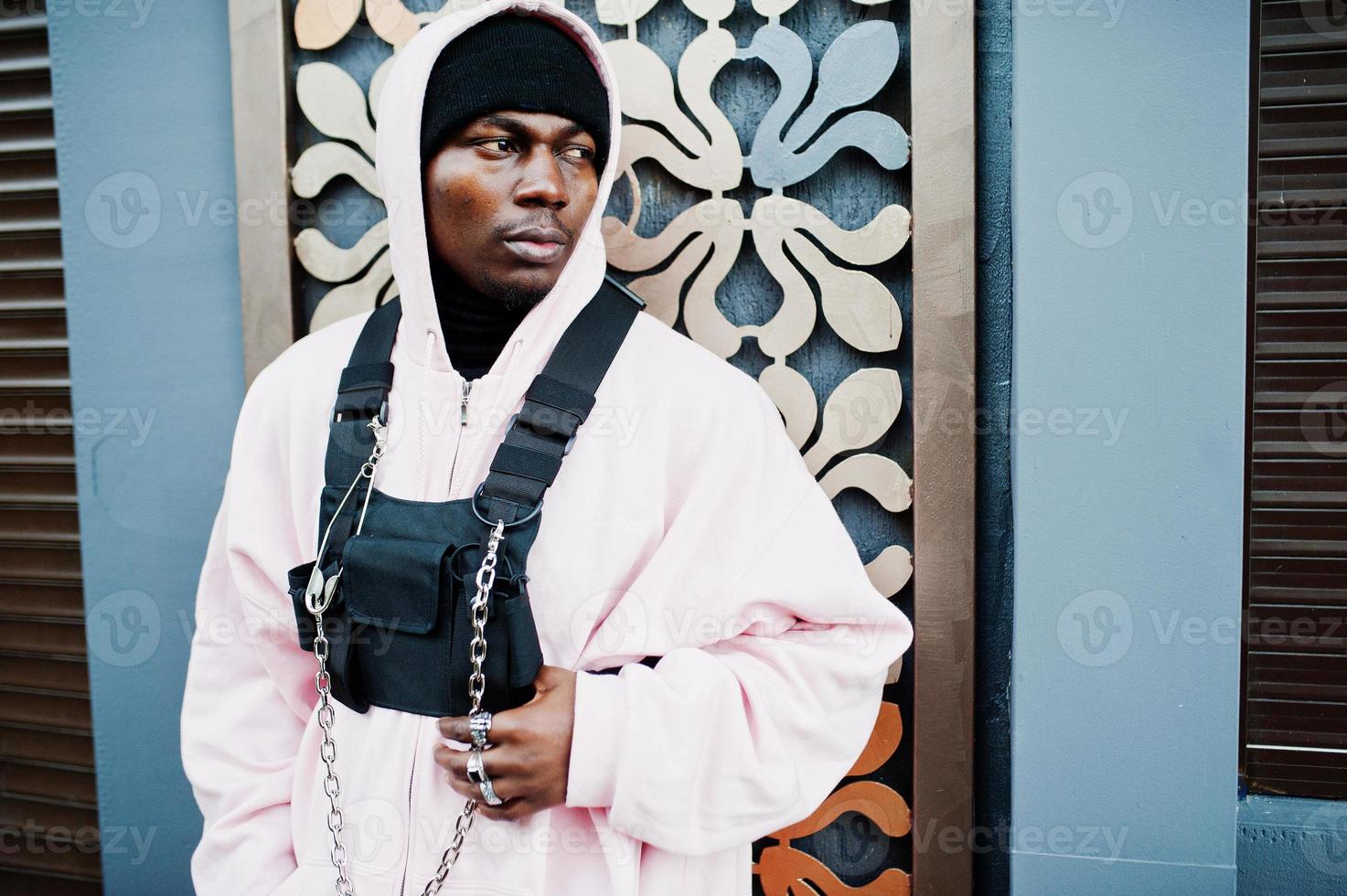 elegante uomo afroamericano in stile urbano in felpa con cappuccio rosa in posa. ragazzo afro rapper. foto