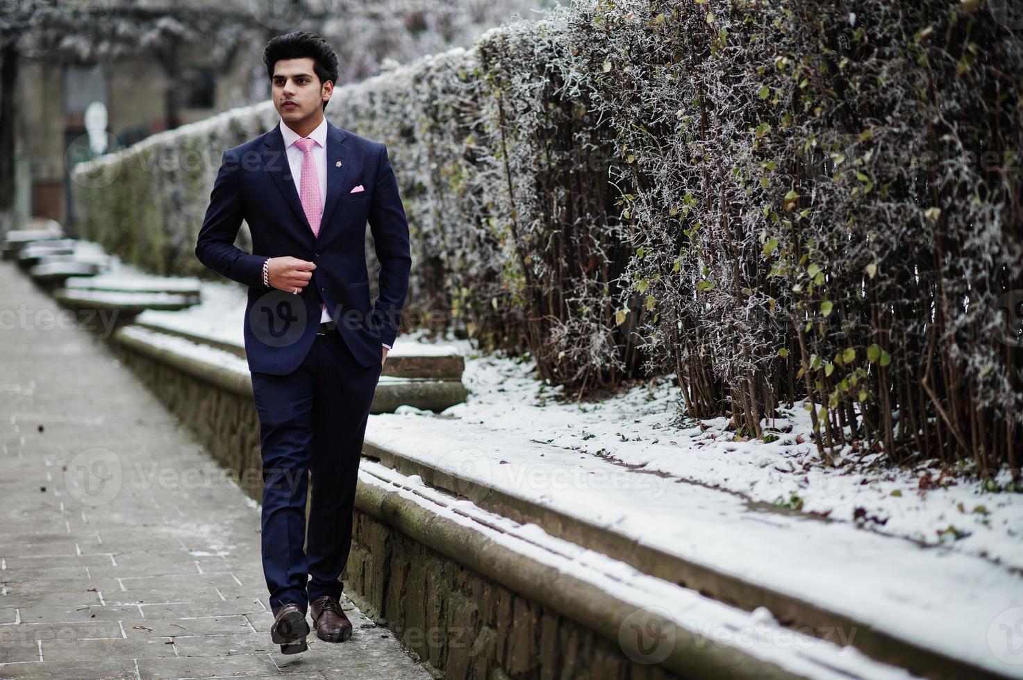 elegante modello uomo macho indiano su abito e cravatta rosa in posa in una giornata invernale. foto