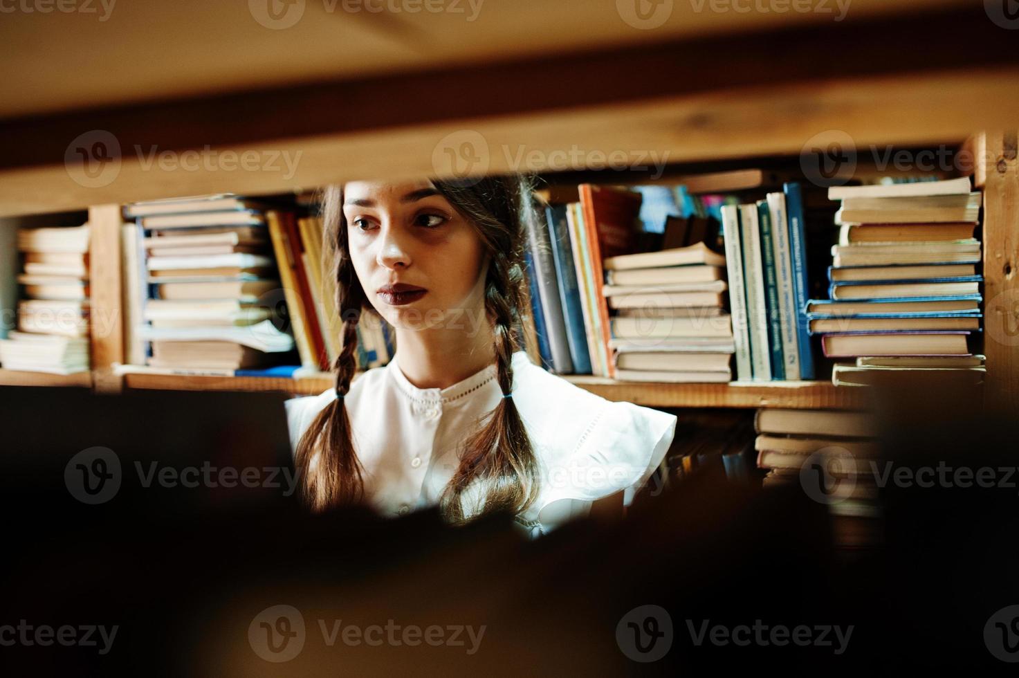 ragazza con le trecce in camicetta bianca alla vecchia biblioteca. foto