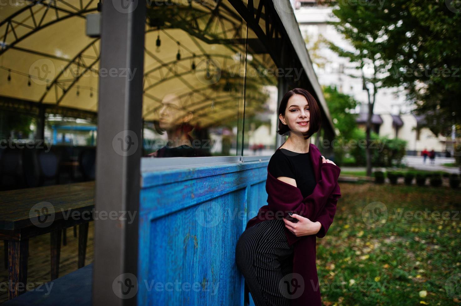 una giovane modella dalle gambe alte, bella ed elegante, al cappotto bordeaux. foto