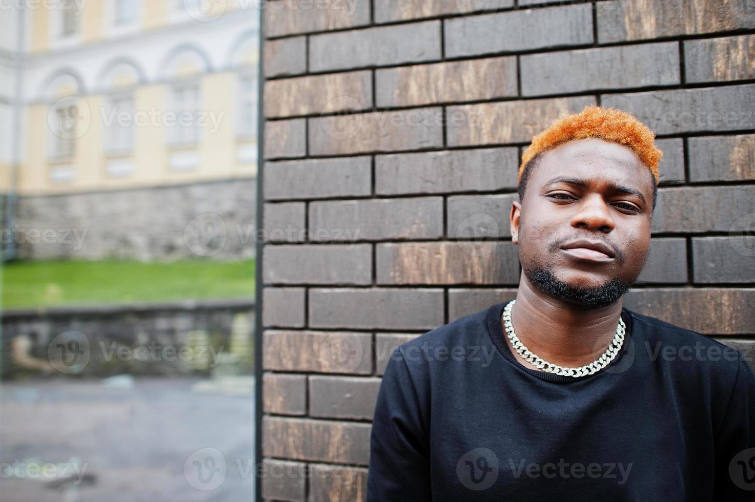 l'uomo africano dai capelli rossi indossa un abito nero in posa all'aperto. foto