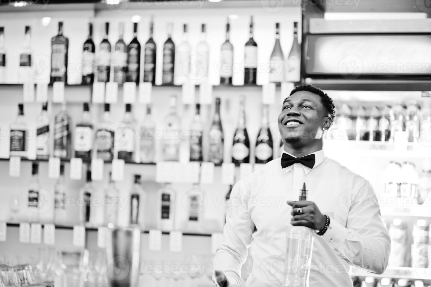 barista afroamericano al bar flair in azione, lavorando dietro il cocktail bar. preparazione di bevande alcoliche. foto