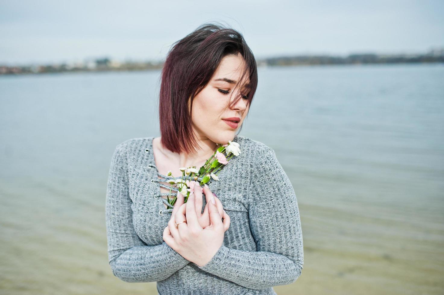 ritratto di ragazza bruna in abito grigio sfondo il lago. foto