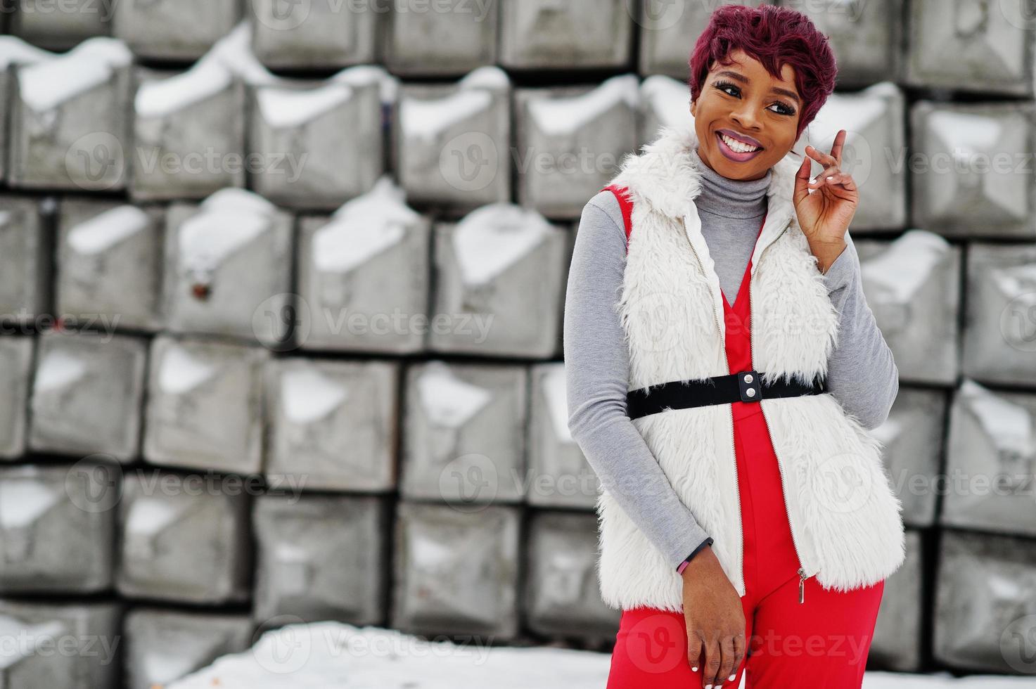 donna afroamericana in pantaloni rossi e giacca di pelliccia bianca poste  in una giornata invernale su sfondo di pietra innevata. 10497475 Stock  Photo su Vecteezy