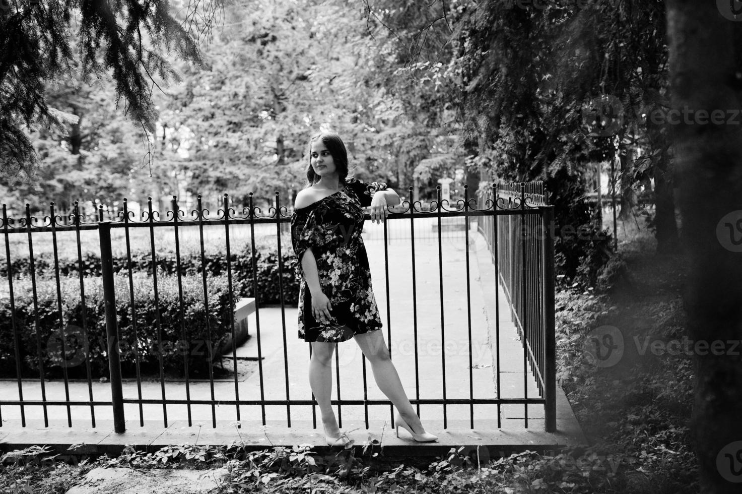 ritratto di una ragazza con un vestito in posa vicino al recinto. foto