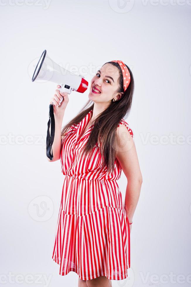 ritratto di una giovane e bella donna in abito rosso che parla nel megafono. foto