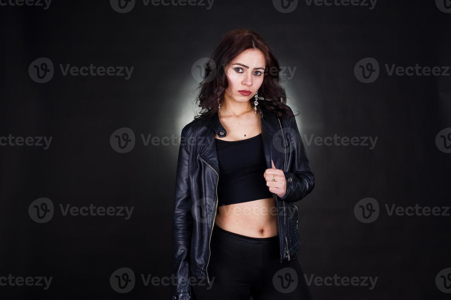 ritratto in studio di ragazza bruna sexy in giacca di pelle nera su sfondo nero. foto