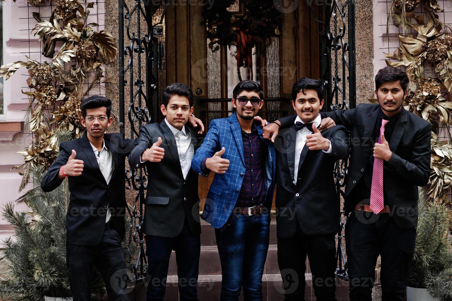 un gruppo di 5 studenti indiani in giacca e cravatta posato all'aperto e mostra il pollice in su. foto
