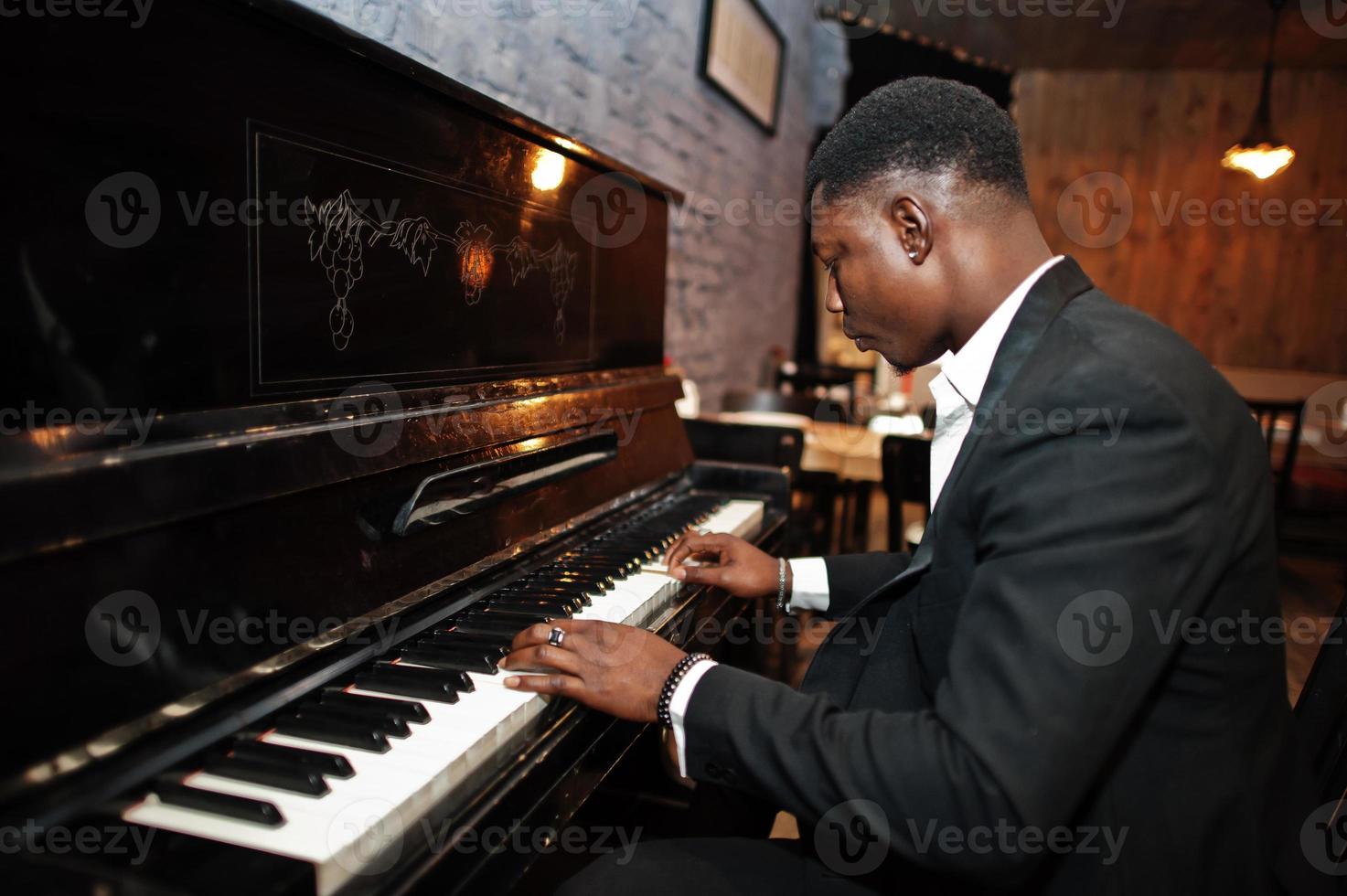 forte e potente uomo afroamericano in abito nero suona il pianoforte. foto