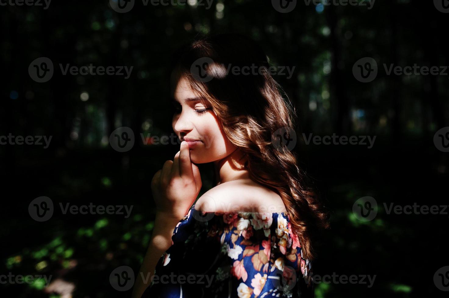 ritratto di una favolosa ragazza in un bel vestito con un'elegante acconciatura riccia in posa nella foresta o nel parco. foto