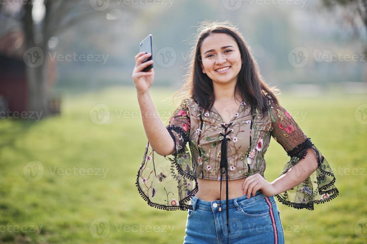 bella ragazza modello latino dell'Ecuador indossa jeans posati in strada con il telefono cellulare. foto