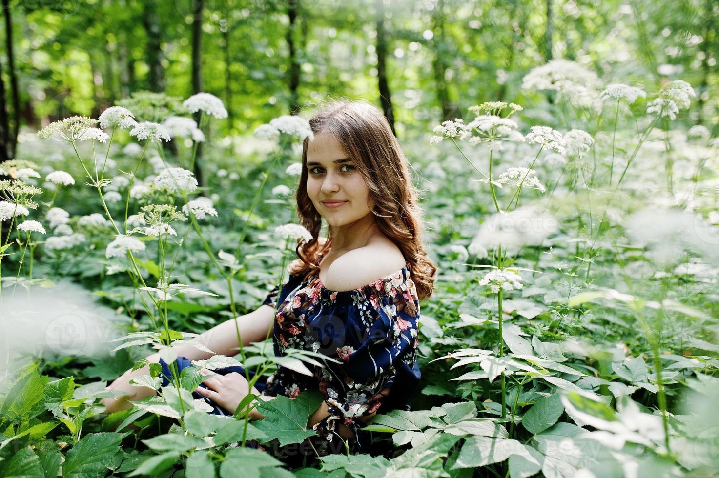 ritratto di una favolosa ragazza in un bel vestito con un'elegante acconciatura riccia in posa nella foresta o nel parco. foto