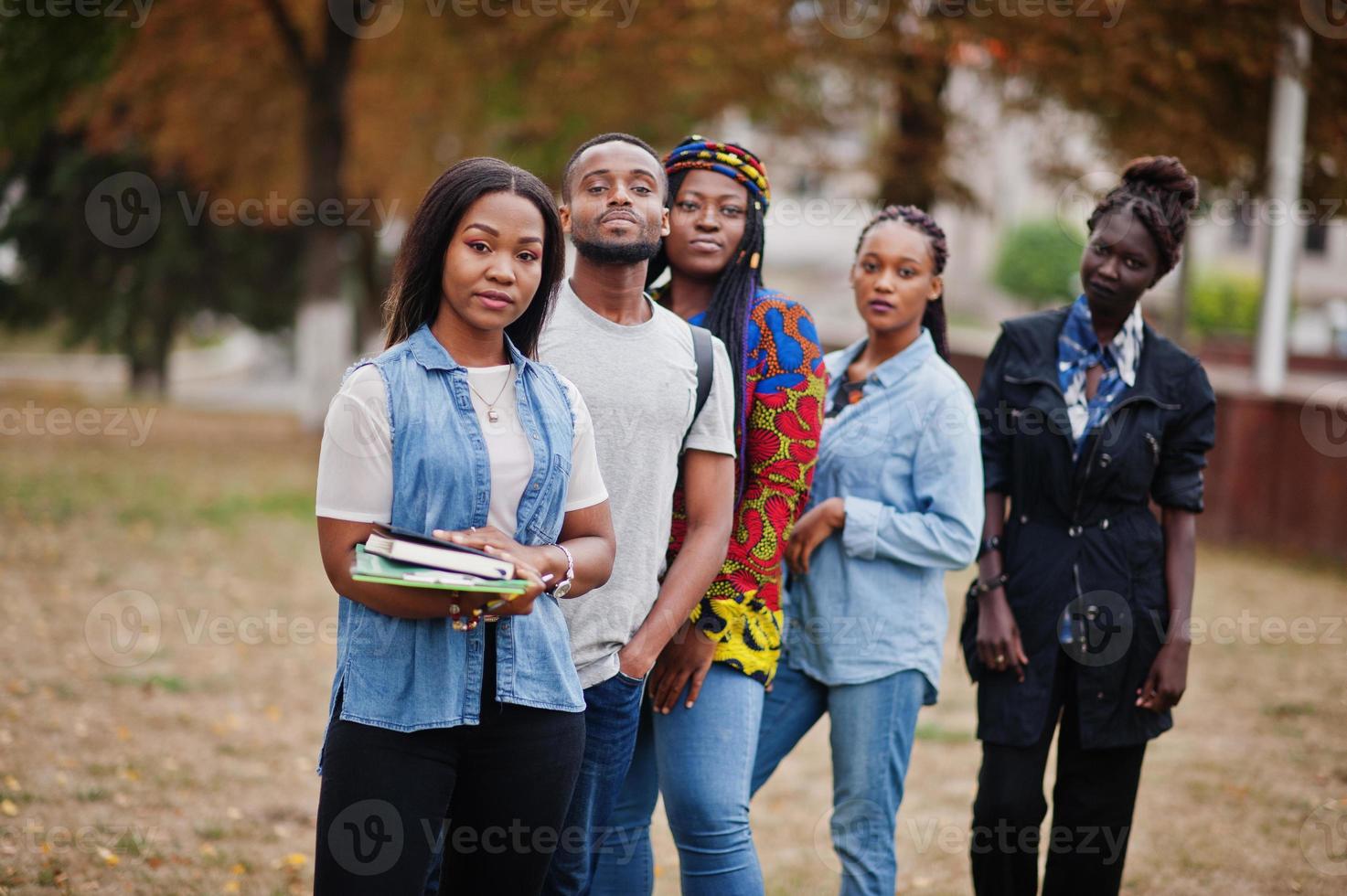 fila di studenti universitari africani del gruppo cinque che trascorrono del tempo insieme nel campus nel cortile dell'università. amici afro neri che studiano. tema dell'educazione. foto