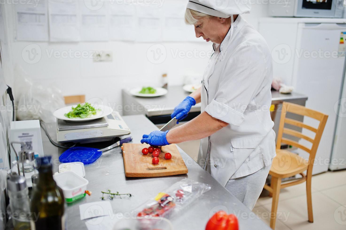 chef femminile che prepara insalata nella cucina del ristorante italiano. foto