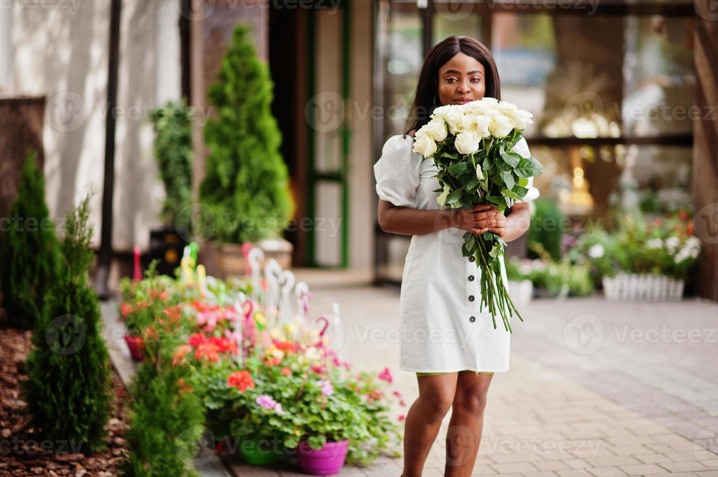 bella ragazza afroamericana con in mano un mazzo di fiori di rose bianche su appuntamenti in città. imprenditrice nera con un mazzo di fiori. foto