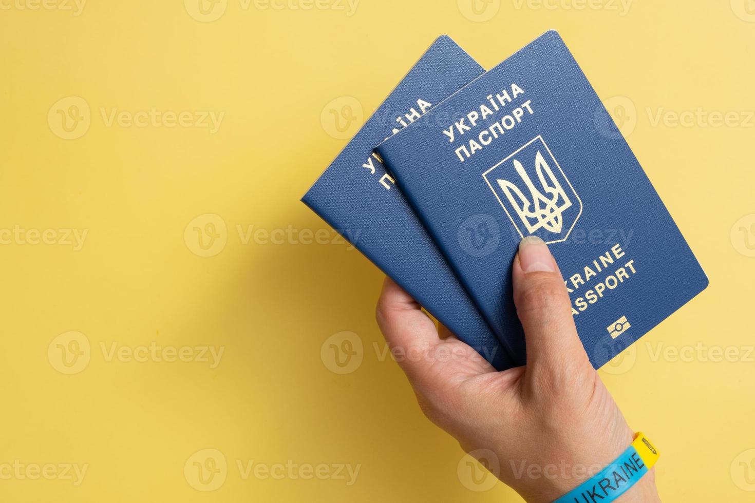 passaporti di un cittadino ucraino in una mano femminile su sfondo giallo, primo piano. iscrizione nel passaporto ucraino ucraino foto
