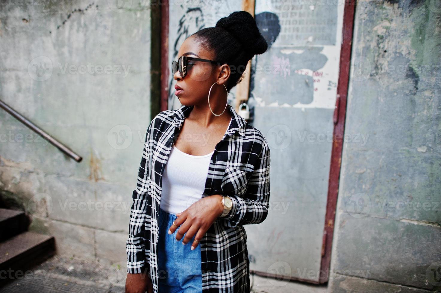 ragazza afroamericana hip hop su occhiali da sole e pantaloncini di jeans. ritratto di moda di strada casual di donna nera. foto