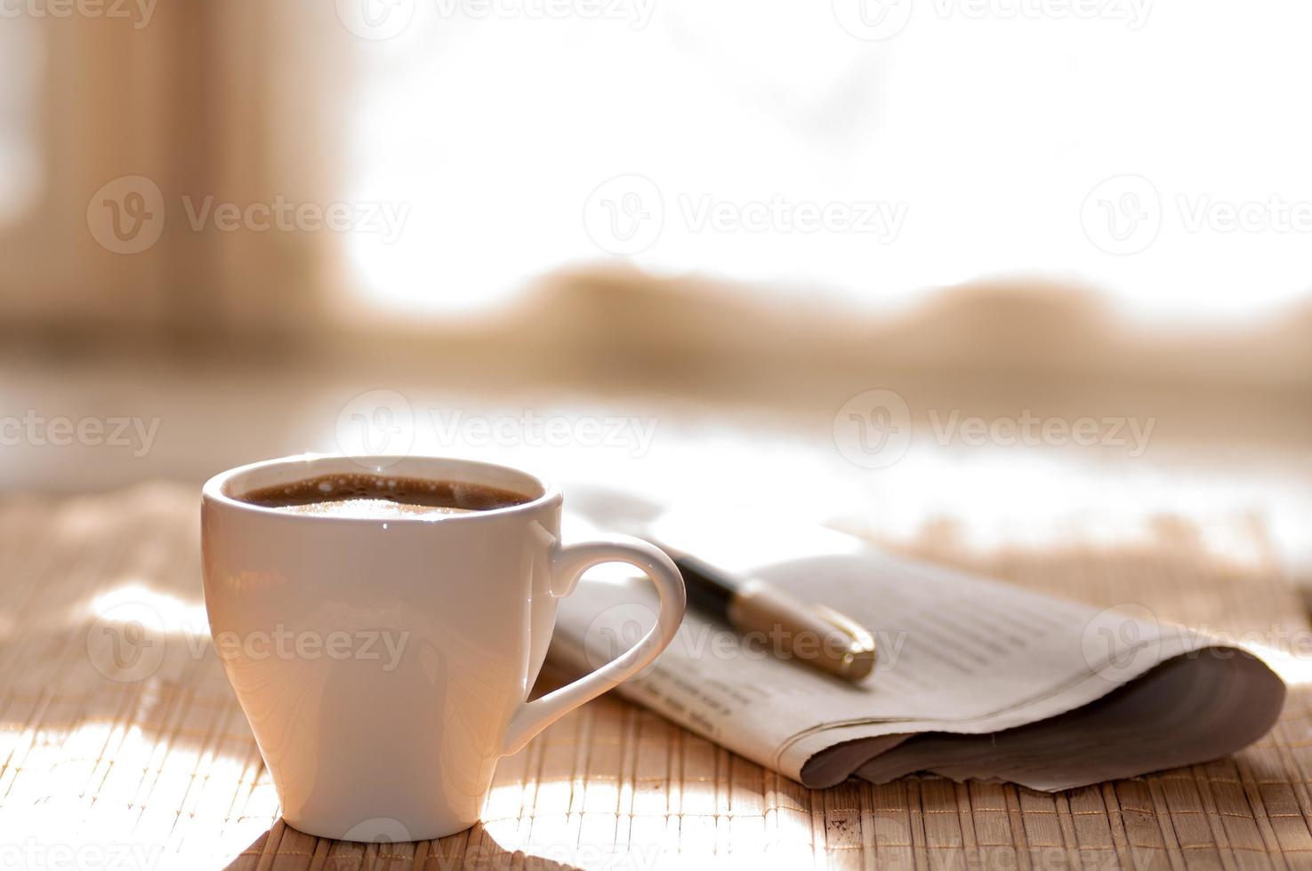 tazza di caffè nero, giornale e una penna foto