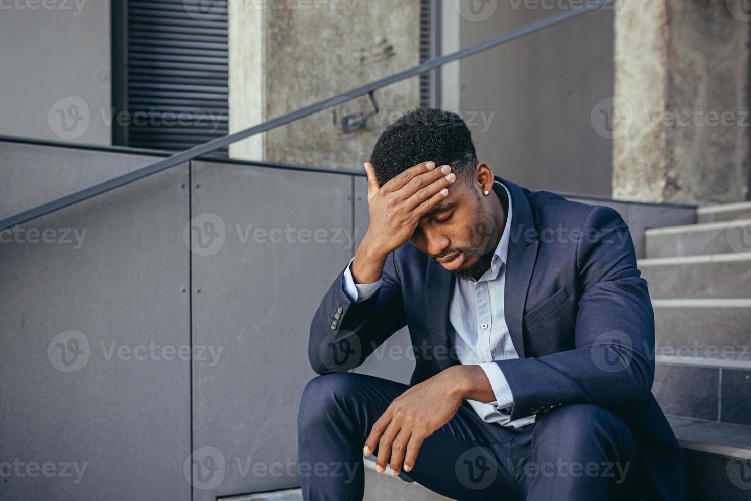 uomo d'affari africano seduto frustrato sulle scale depresso dai risultati del suo lavoro foto